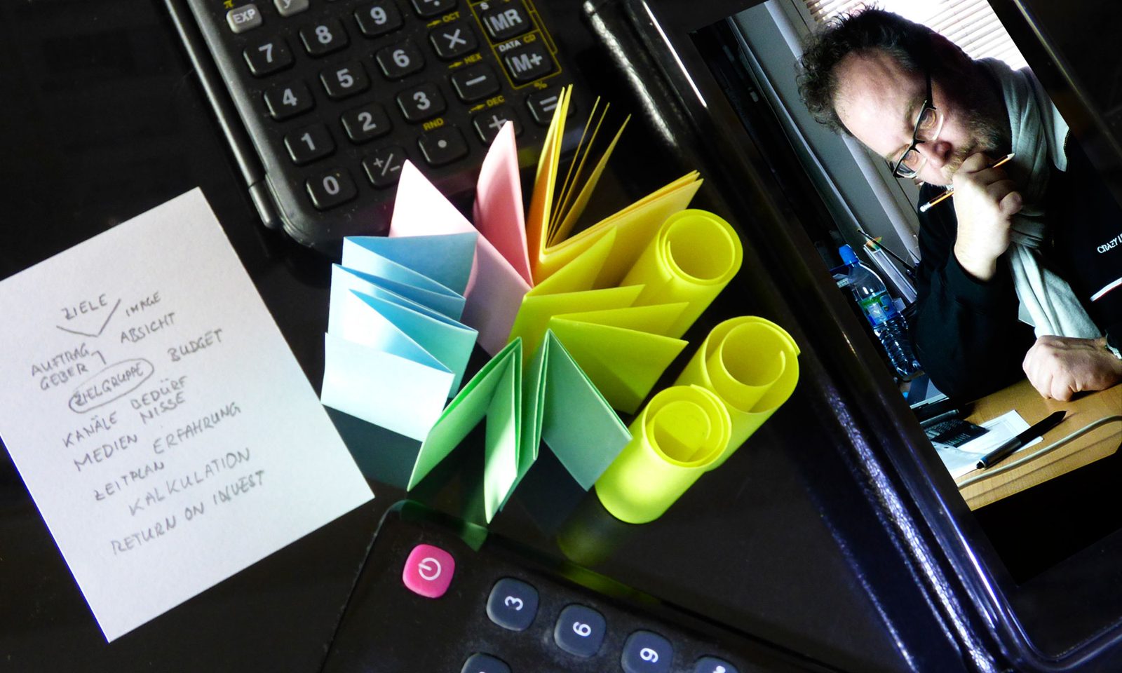Konzeptarbeit am Schreibtisch: Skizzen, Moodboard-Fächer aus Papier und Andreas Wick bei der Arbeit.